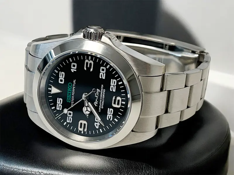 Der Seiko Mod Air King 2022 ist eine Fliegeruhr mit einem markanten und stilvollen Design. Das Edelstahlgehäuse und das Armband verleihen ihr eine robuste und zugleich elegante Optik. Das schwarze Zifferblatt bietet eine klare Ablesbarkeit, mit großen arabischen Ziffern und auffälligen Minutenmarkierungen, die speziell für Piloten entwickelt wurden. Die Kombination aus präziser Verarbeitung und praktischen Funktionen macht diese Uhr zu einem beeindruckenden Accessoire für Liebhaber von Fliegeruhren.