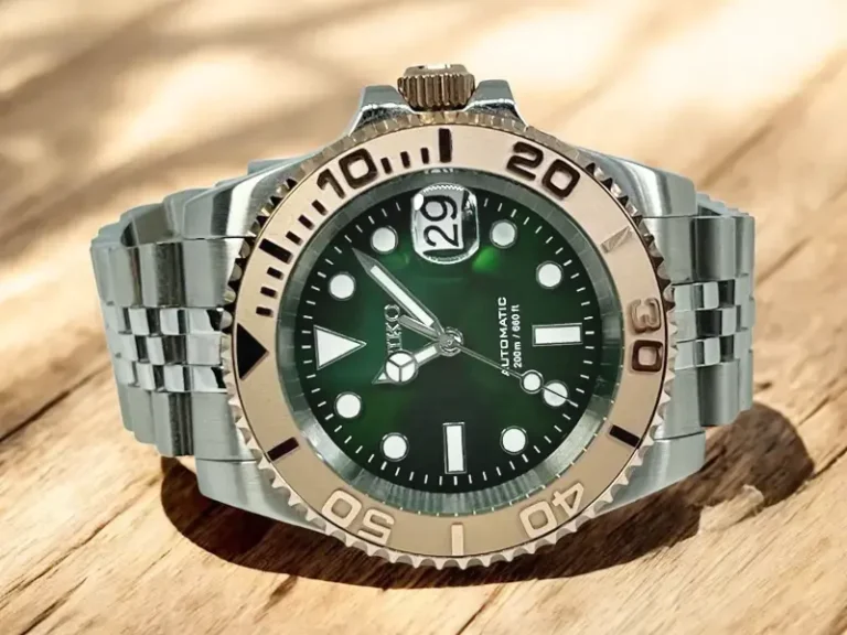 Frontalansicht des Seiko Mod Yacht‑Master mit smaragdgrünem Zifferblatt, roségoldener Lünette und Jubilee‑Edelstahlarmband auf hellem Holz im Sonnenlicht